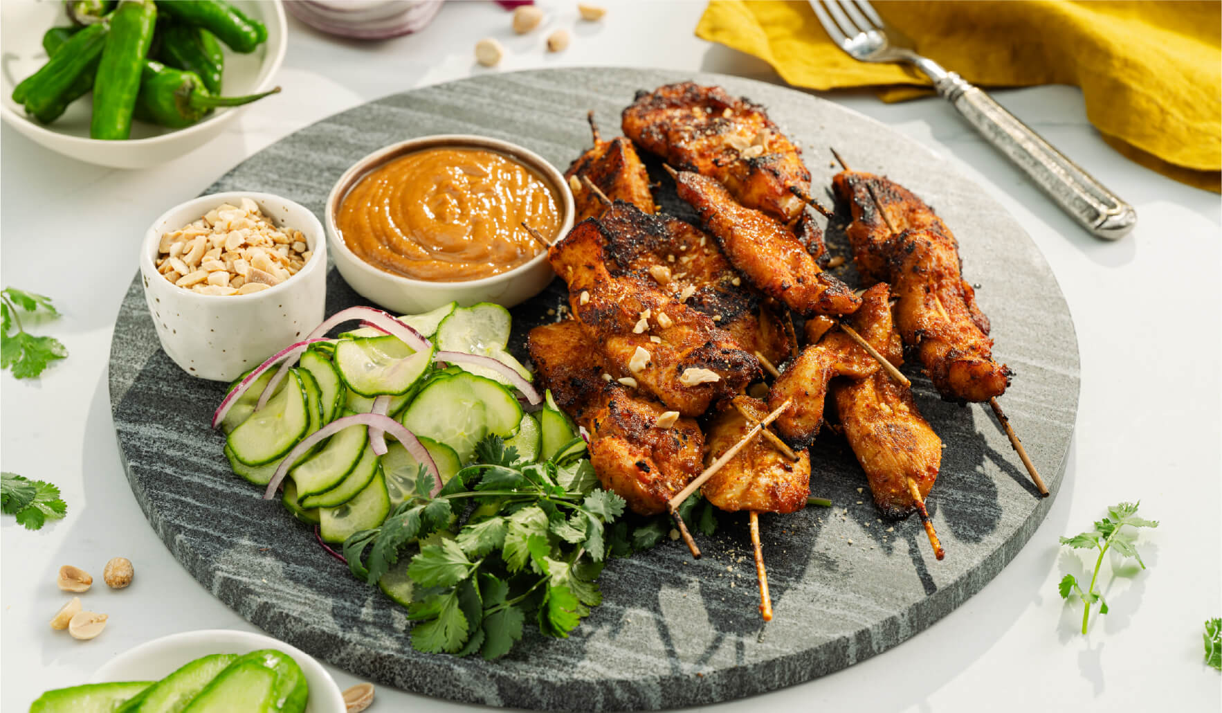 Air fryer chicken satay skewers served with peanut sauce and pickled cucumber salad