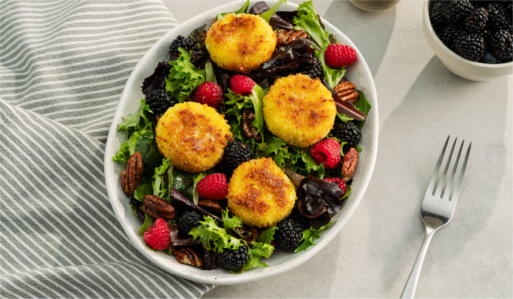 Crispy goat cheese salad with berries, maple pecans, and mixed greens