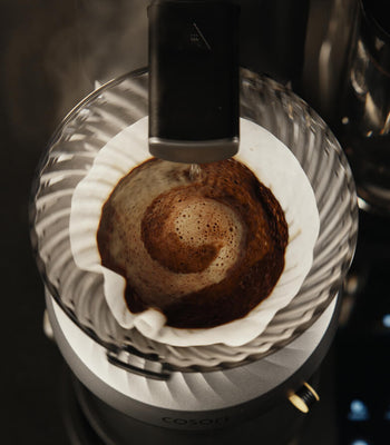 Pour-over coffee dripper with bloomed grounds, showing the coffee brewing process