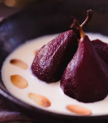 dark red bourbon-poached pears served in a bowl of creamy crème anglaise