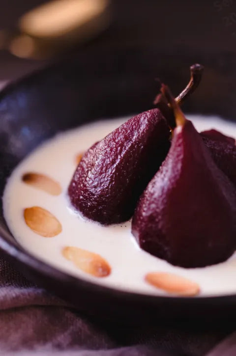 dark red bourbon-poached pears served in a bowl of creamy crème anglaise