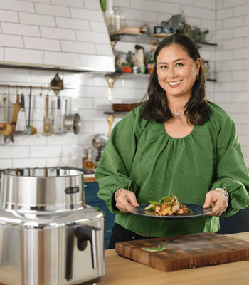 Food content creator Corre Larkin smiling and holding a beautifully plated dish in her kitchen, with the Cosori Iconic air fryer