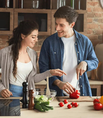 A happy couple preparing fresh ingredients together in a home kitchen.