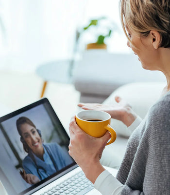 Woman holding a cup of coffee while talking on a video call at home