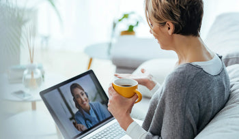 Woman holding a cup of coffee while talking on a video call at home
