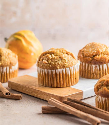 Gluten-free pumpkin spice cupcakes with crumb topping on a board with cinnamon sticks.