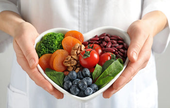 Heart-shaped bowl filled with heart healthy ingredients like vegetables, beans, berries, and nuts