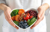 Heart-shaped bowl filled with heart healthy ingredients like vegetables, beans, berries, and nuts