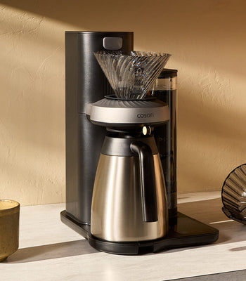 A Juni automated pour-over coffee machine, carafe, and tools on a home kitchen countertop.