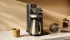 A Juni automated pour-over coffee machine, carafe, and tools on a home kitchen countertop.