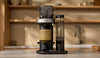 A Cosori Juni automated pour-over coffee maker standing on a kitchen countertop.