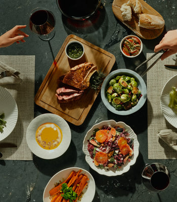 Top-down view of a large dinner spread including steak, roasted vegetables, and salad, perfect for family meals.