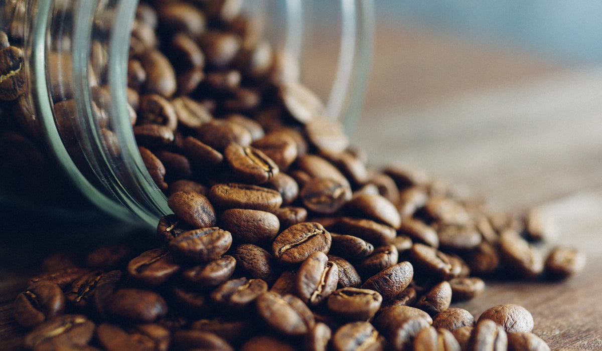 Roasted coffee beans spilling from a jar, symbolizing the natural source of caffeine in coffee