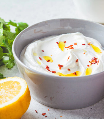 creamy whipped feta dip drizzled with olive oil and chili flakes in a grey bowl