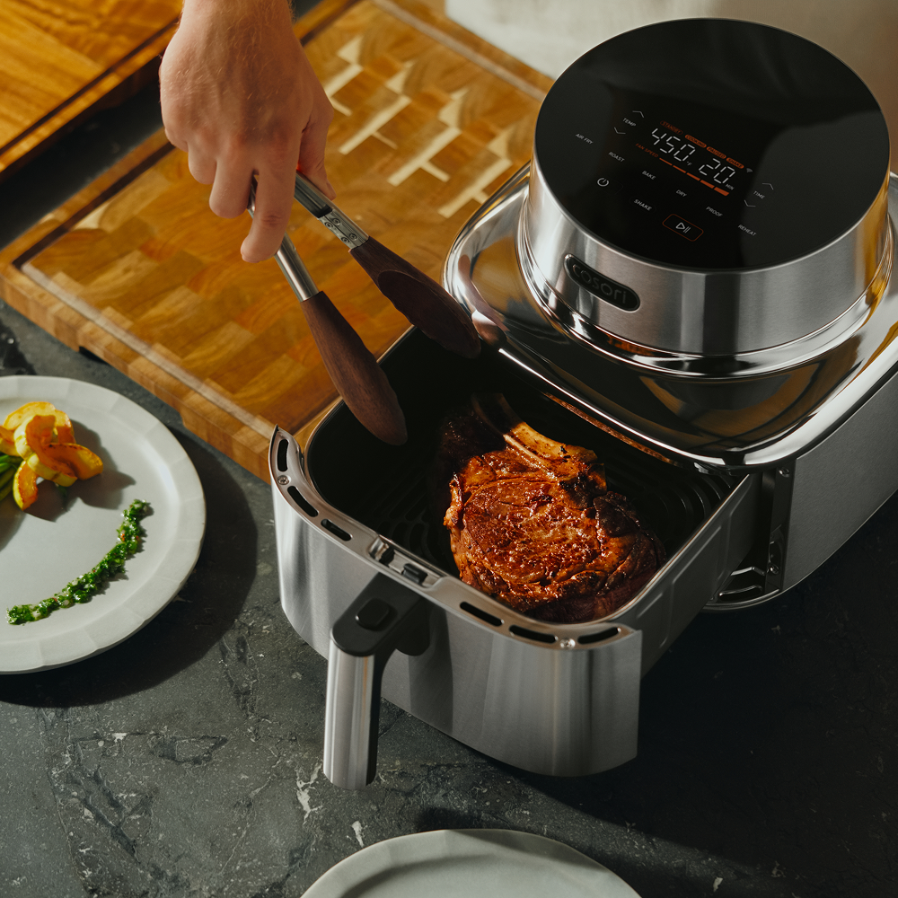 Air fryer with a browned steak in the basket