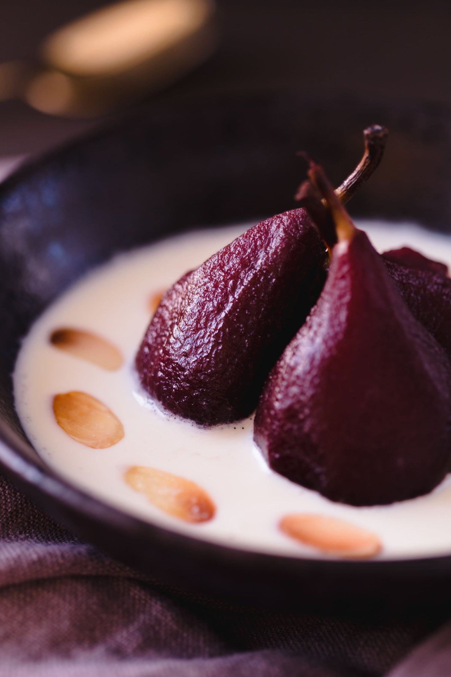 dark red bourbon-poached pears served in a bowl of creamy crème anglaise