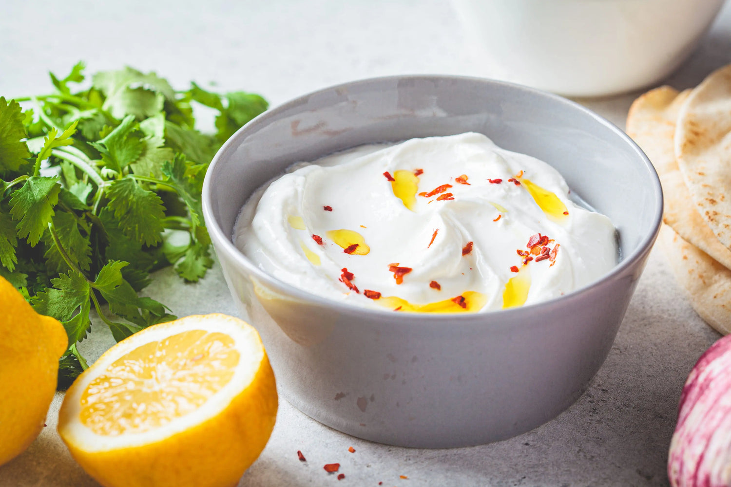 creamy whipped feta dip drizzled with olive oil and chili flakes in a grey bowl