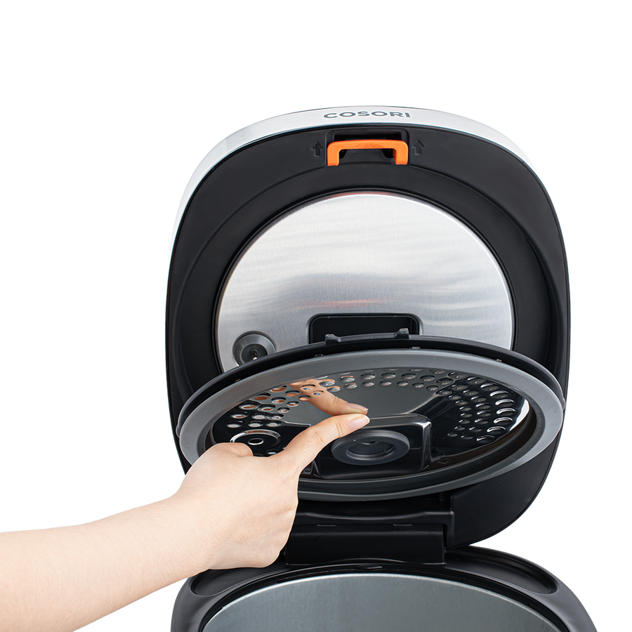 Hand demonstrating how to remove the inner lid of the Cosori Rice Cooker with a push button.