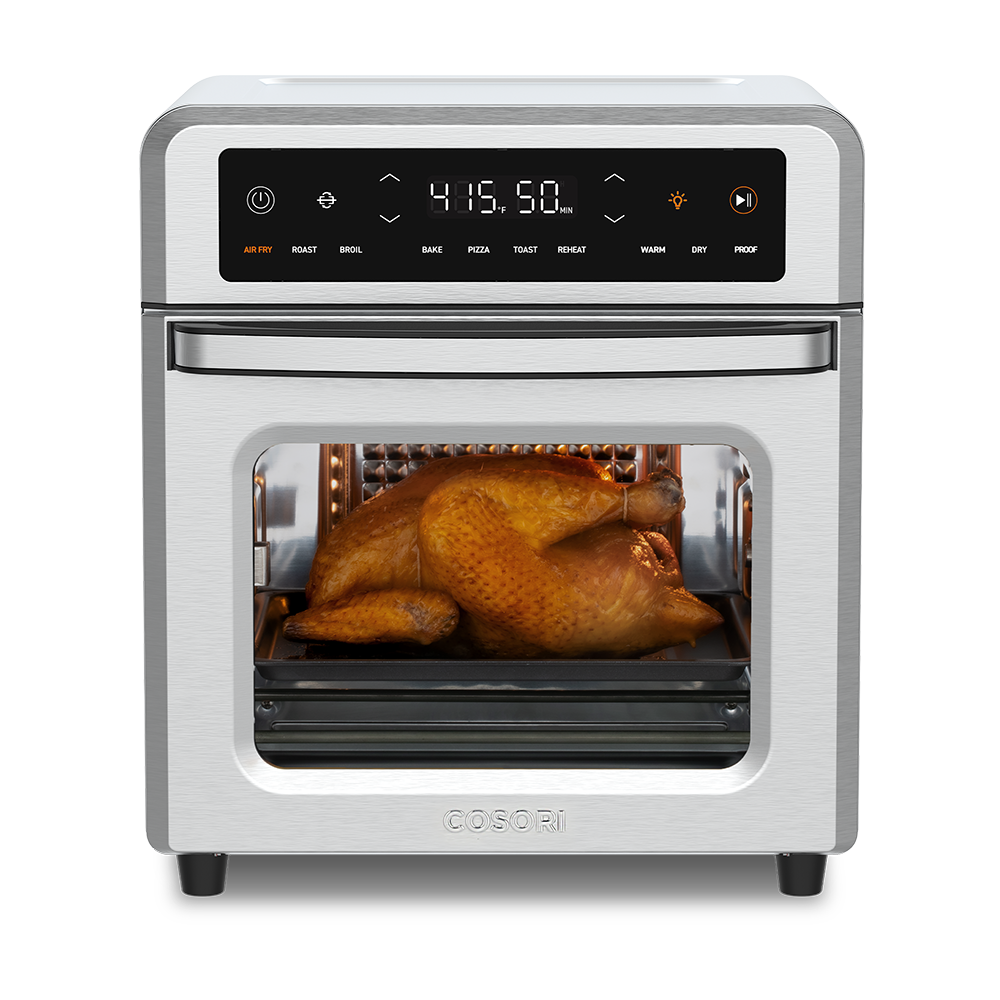 Cosori 13-Quart Air Fryer Oven with a whole roasted chicken cooking inside. Stainless steel finish